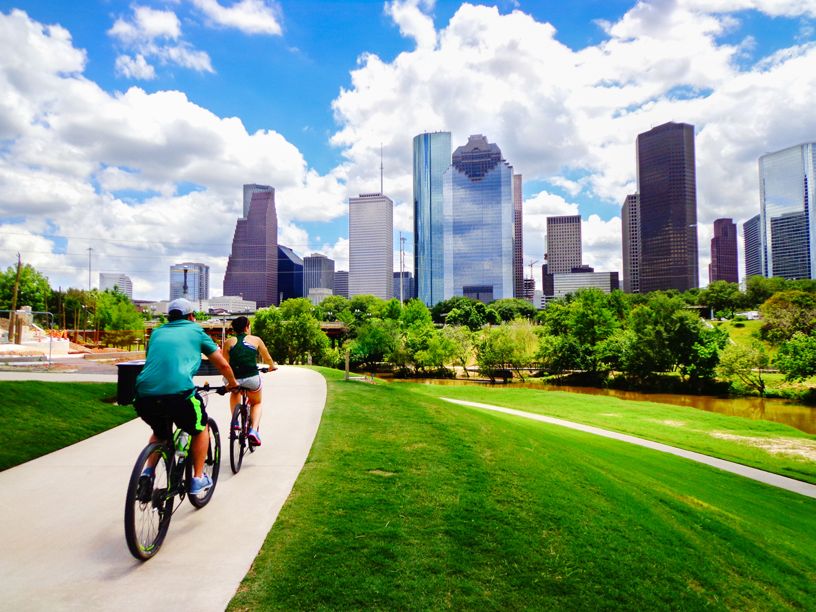 Couple riding bikes on path in downtown Houston Park