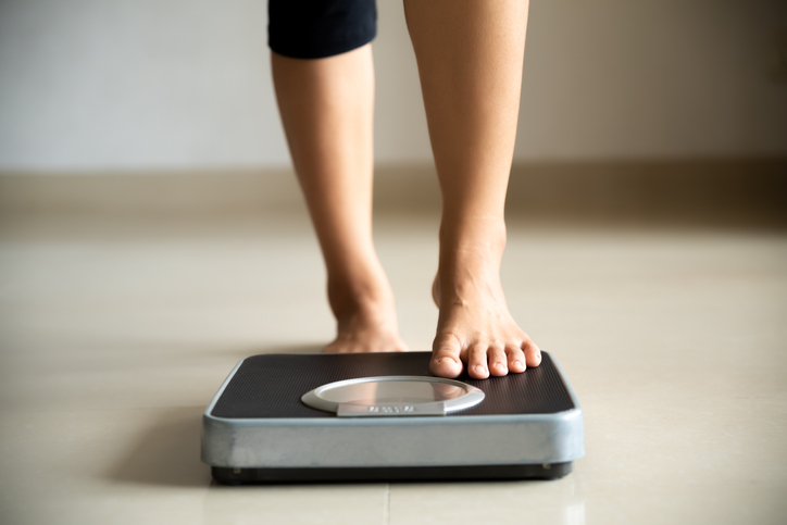 Female leg stepping on weigh scales. Healthy lifestyle, food and sport concept