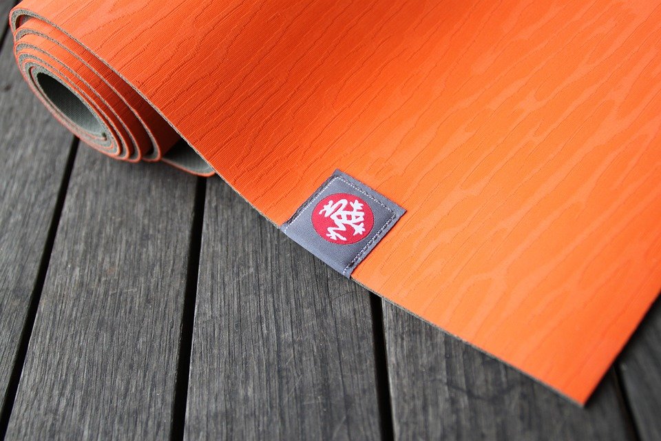 an orange yoga mat rolled on the floor