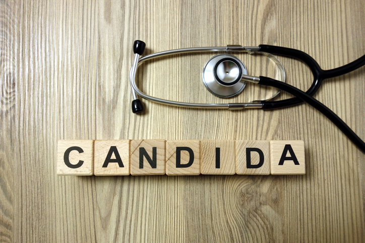 Candida word with stethoscope on wooden background