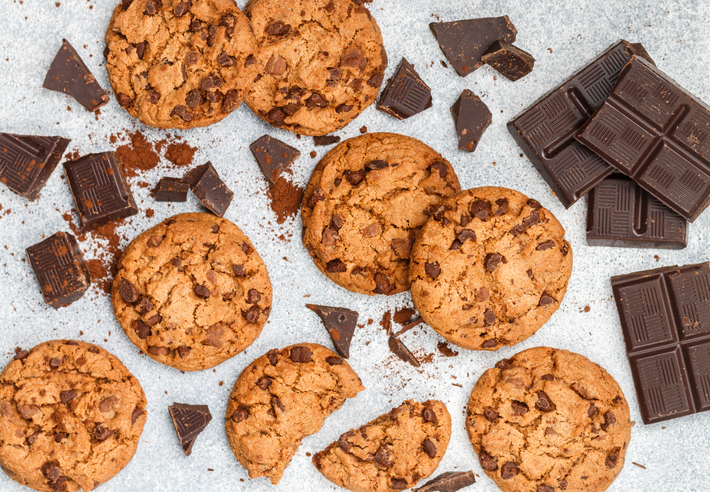 Freshly baked homemade crunchy cookies with chocolate chips, peanut butter or salted caramel. A delicious treat for gourmets. Biscuits on a grey concrete background. Selective focus, top view