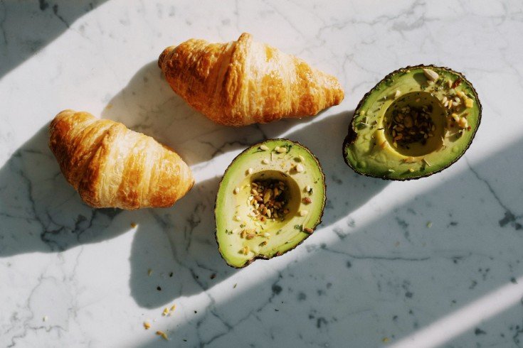 avocado cut in half and two croissants
