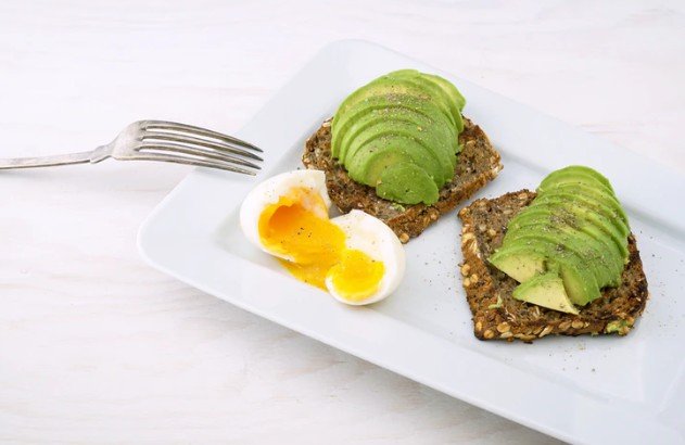 thinly sliced avocado served with boiled eggs and toast