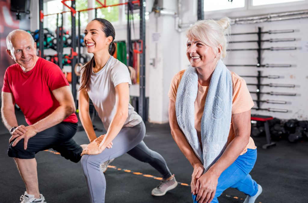 Personal trainer with senior couple doing rehab exercises at the gym