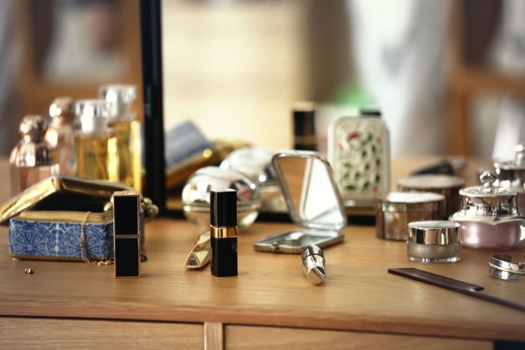 lipsticks and some cosmetics put on a dressing table in front of a mirror