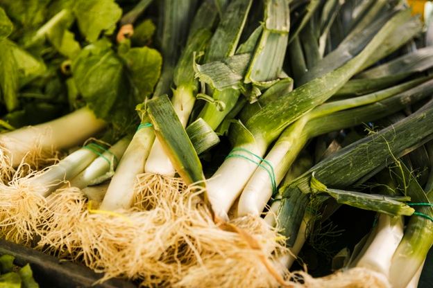 An image showing a bunch of fresh leek on a market crate.