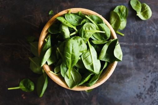 Raw spinach in a wooden bowl