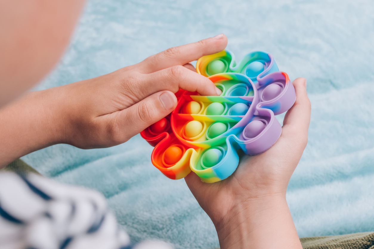 a boy playing with a rainbow pop it fidget toy
