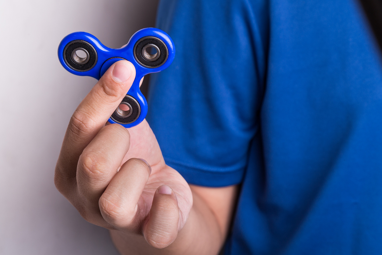 a teenager holding a fidget spinner